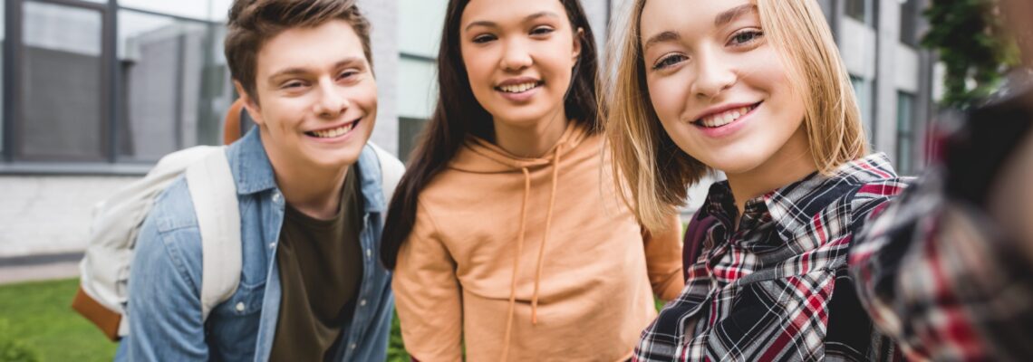 happy teenagers taking selfie, smiling and looking at camera